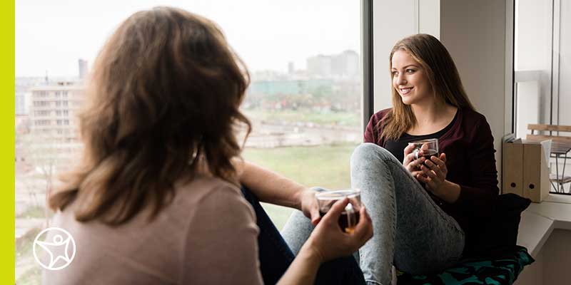 A mother and her teenage daughter enjoying tea and conversation.