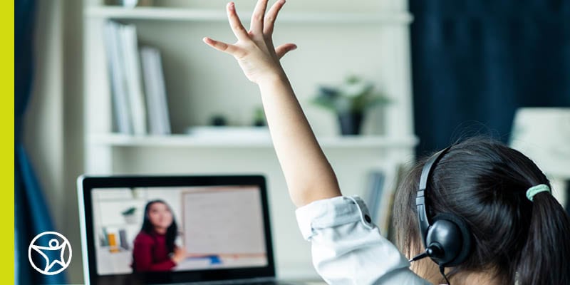 Image of a young female student who is raising her hand while taking an online class.